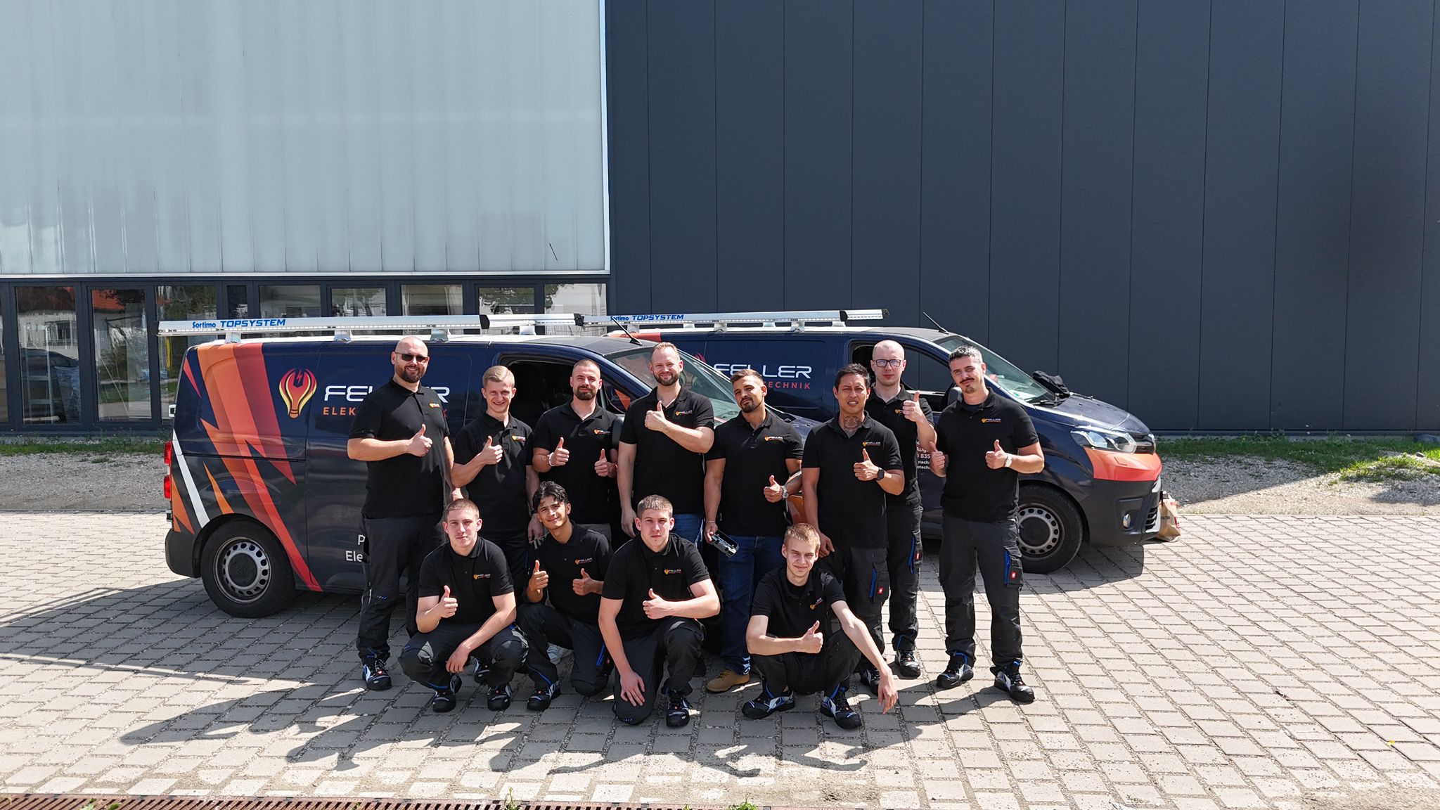 Das Team von Feller Elektrotechnik vor den Firmenfahrzeugen